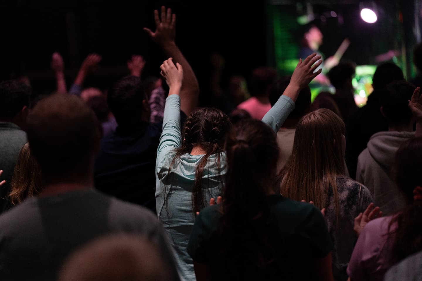 youth worshipping in church with arms raised